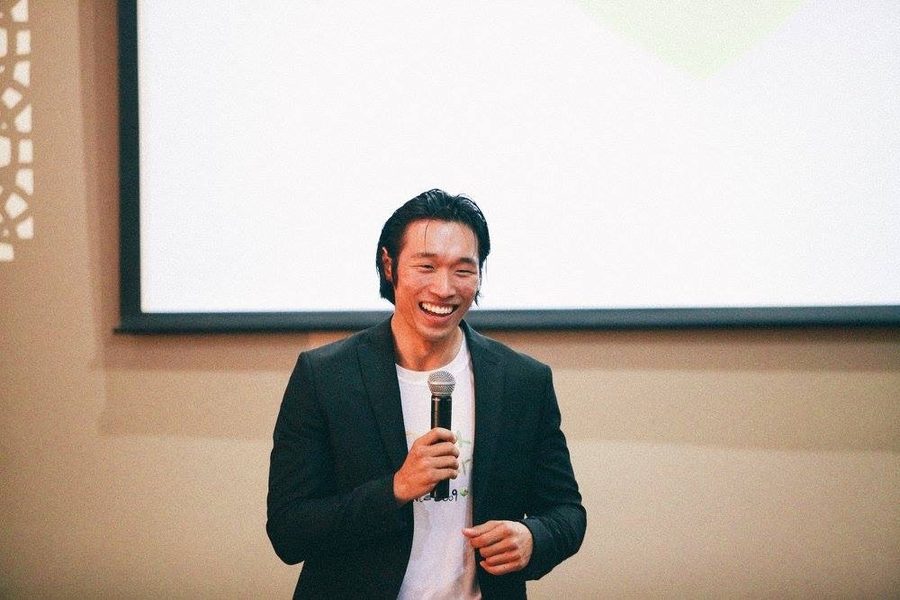 Chris speaking on stage with a microphone, laughing